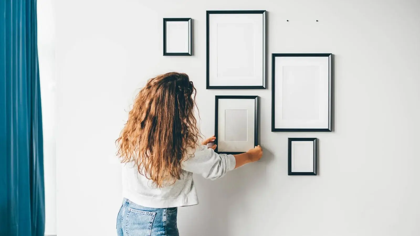 A person hanging a framed poster on a wall